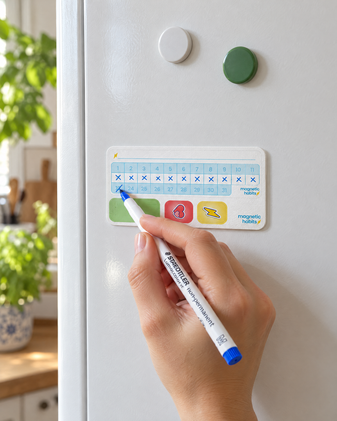 Ein Habit Tracker am Kühlschrank, eine Hand setzt das zwölfte Zeichen